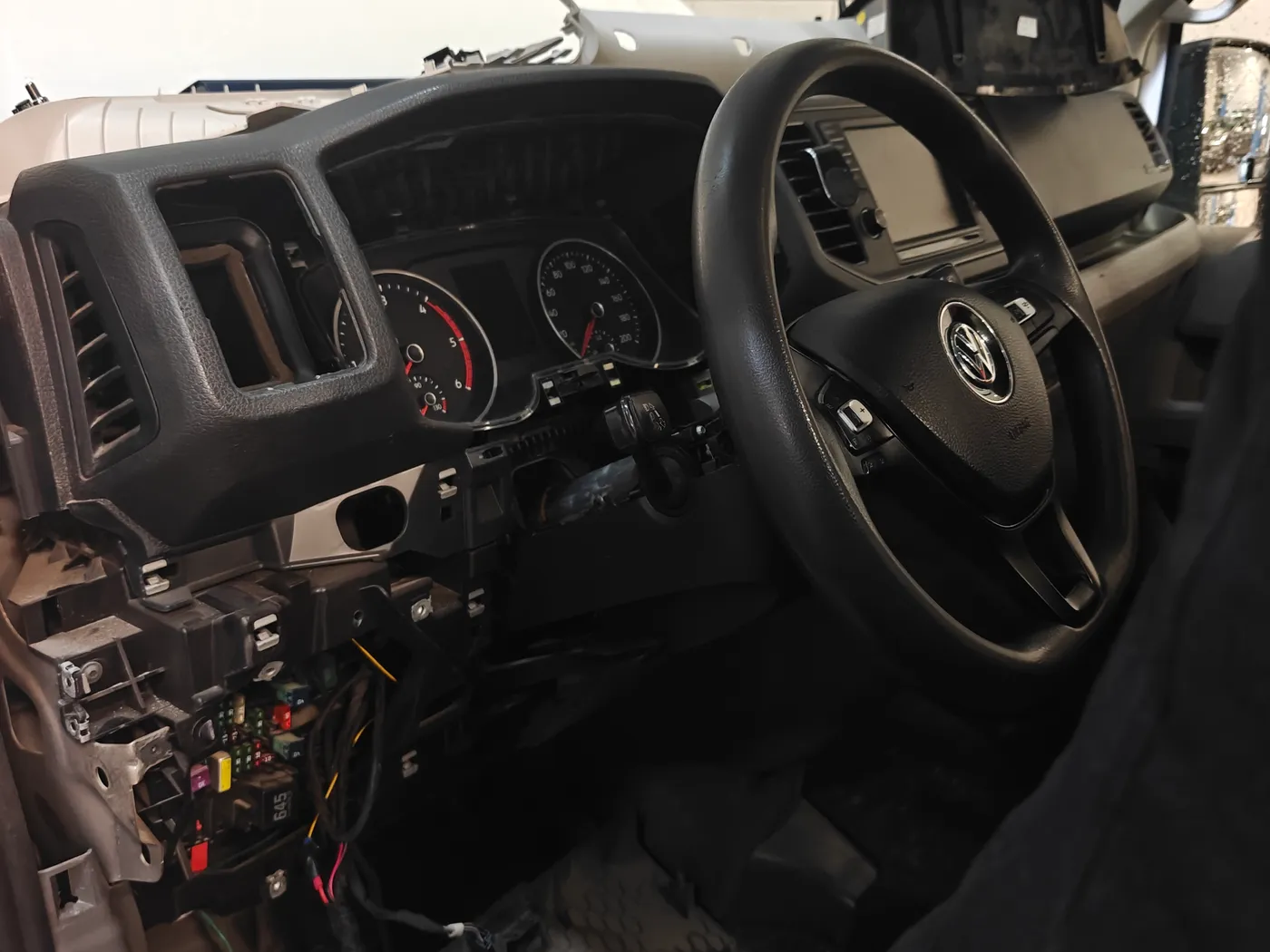 Cabine van een Volkswagen Crafter met gedemonteerd dashboard en open zekeringkast tijdens de tachograaf-inbouw