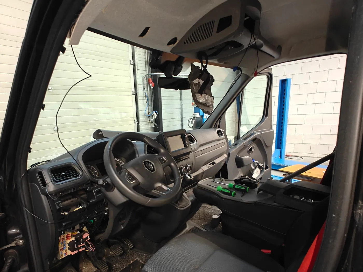 Cabine van een Renault Master in de werkplaats met gedemonteerd zijpaneel en bekabeling langs de A-stijl, dezelfde bus als de Opel Movano tot 2021